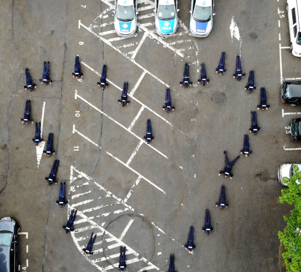 Widok z góry. Policjanci robiący pompki, patrząc z góry na ustawienie policjantów, widzimy kształt serca. 