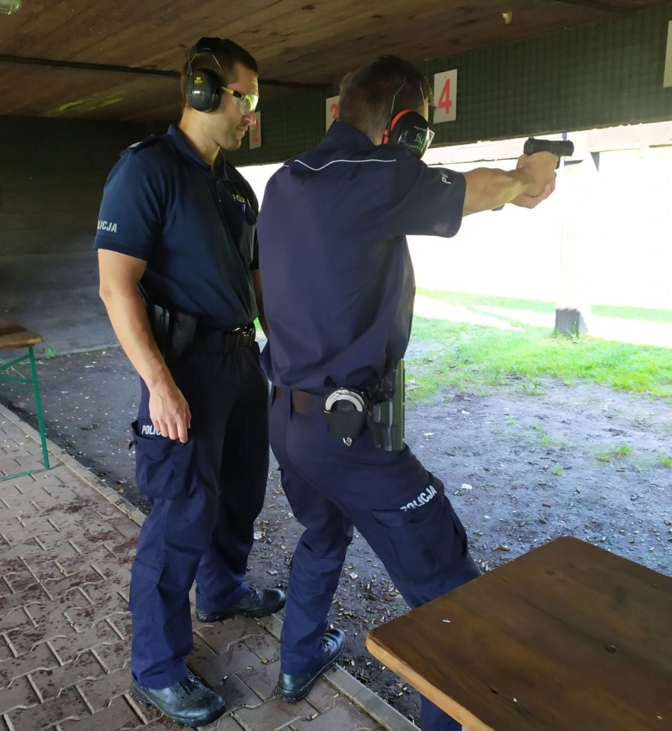 Na zdjęciu policjant nadzorujący strzelanie oraz stróż prawa biorący udział w doskonaleniu zawodowym. 