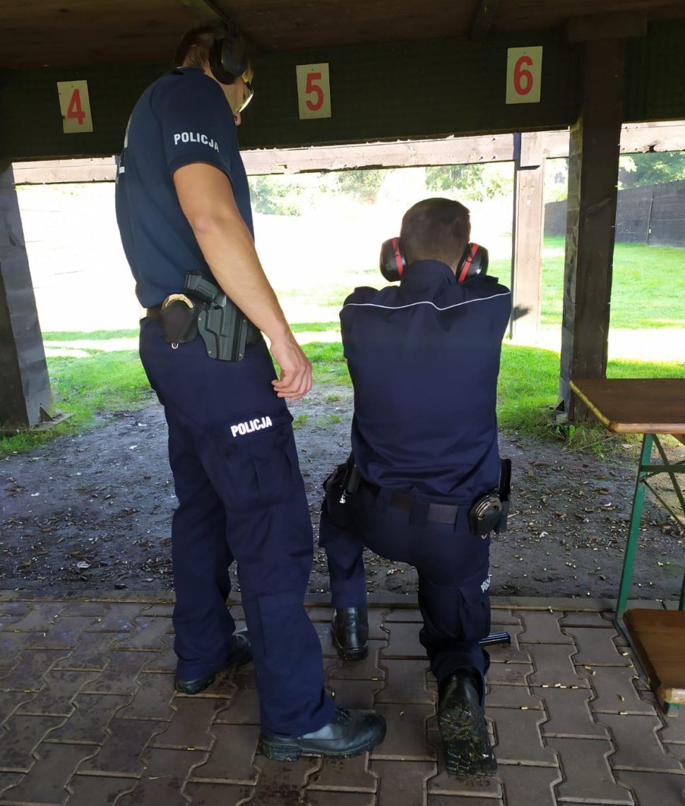 Na zdjęciu policjant nadzorujący strzelanie oraz stróż prawa biorący udział w doskonaleniu zawodowym. 