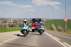 Zdjęcie przedstawia policyjne motocykle oraz straż pożarna podczas przejazdu