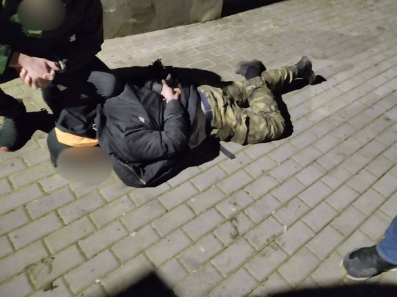 Zdjęcie przedstawia policjanta oraz zatrzymanego mężczyznę, który leży na ziemi