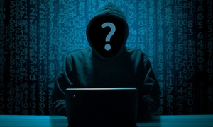 Obrazek przedstawia cyberprzestępcę siedzącego za komputerem